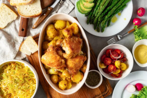 Home dinner table with set of various food from baked new potatoes with chicken thighs, vegetables and salads top view, tasty and healthy food